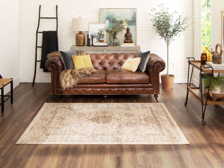 Brown wood-look floors in a bright boho living room complement a leather couch.